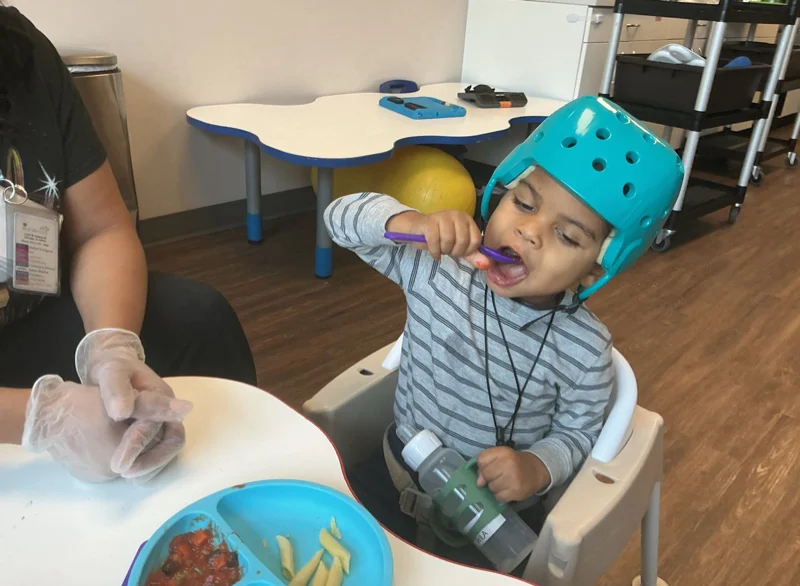 child with spoon in mouth eating lunch