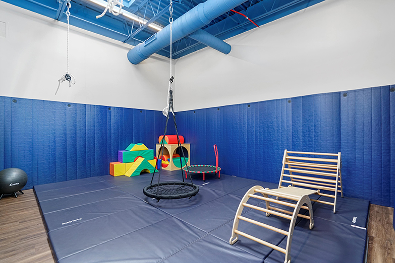 Interactive Therapeutic Sensorimotor gym at our West Loop Chicago location. Includes a therapeutic web swing, a child-sized trampoline, large colorful blocks for gross motor play, and a climbing ladder.