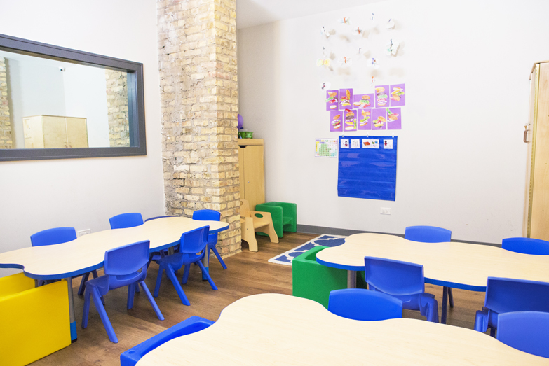 Therapeutic preschool or kindergarten classroom from our Northcenter Chicago location. There are three child-sized tables with blue chairs.