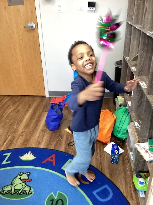Child at Blue Bird Day blowing on a pinwheel
