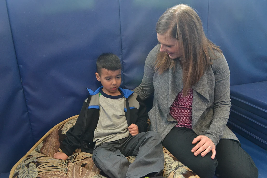 Upset child sitting on cushion next to therapist