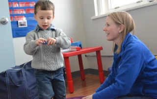 Child talking with woman while playing with a block
