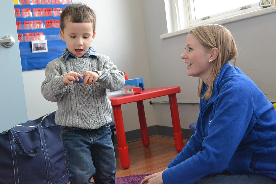Child talking with woman while playing with a block