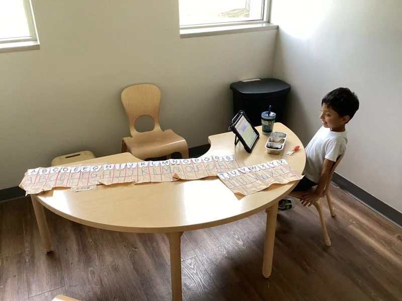 Child at table with alphabet worksheet activity