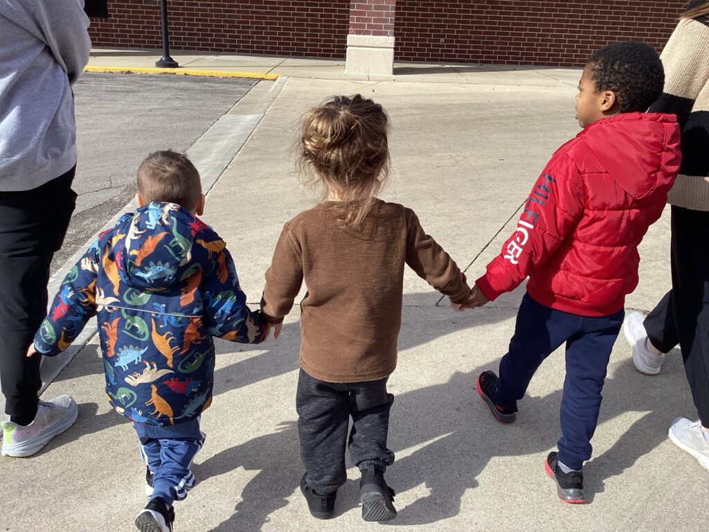 Children holding hands while going on a walk outside at Blue Bird Day West Loop