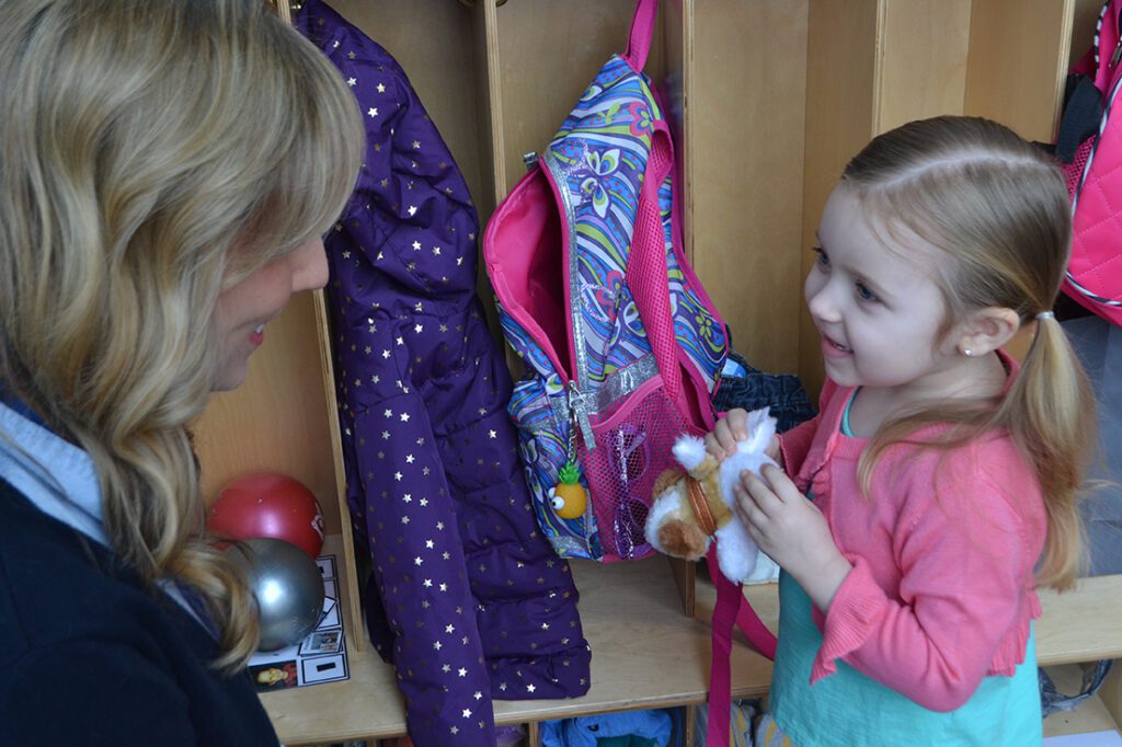 child at cubby with a teacher.
